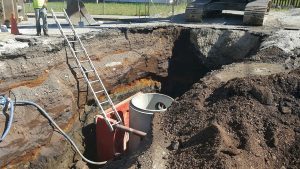 Image showing sewer project requiring local road to be torn up. Various colors are seen in the soil, showing the different types of mine waste present.