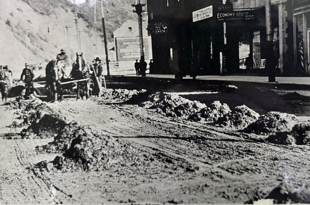 historic image of roadwork being done along Cedar Street in Wallace, Idaho. The former Samuels Hotel is seen in the background.
