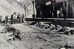 historic image of roadwork being done along Cedar Street in Wallace, Idaho. The former Samuels Hotel is seen in the background.