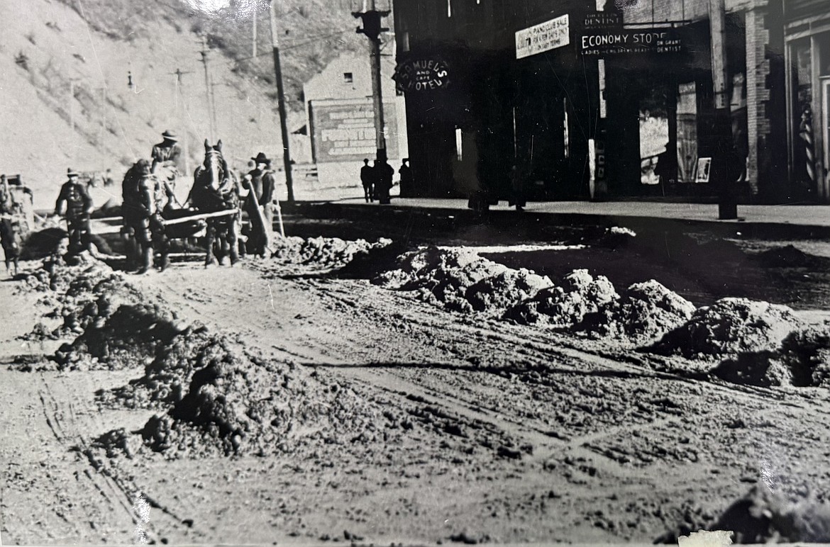historic image of roadwork being done along Cedar Street in Wallace, Idaho. The former Samuels Hotel is seen in the background.